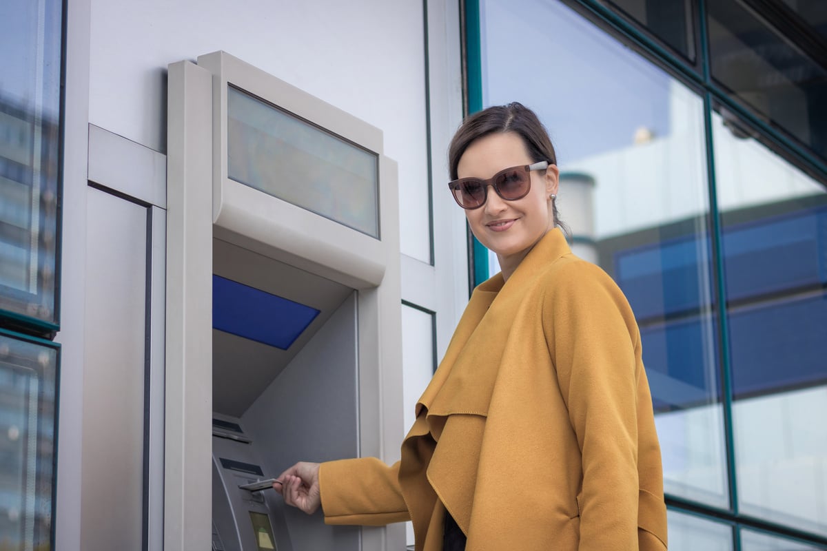 Beautiful Businesswoman Withdrawing Money from Cash Machine.